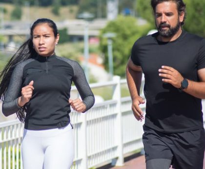 Active couple jogging outdoors on a sunny day, promoting fitness and healthy lifestyle.